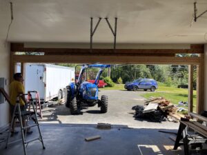 Garage bay view showing a blue tractor holding up the timber header.