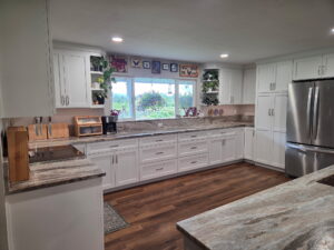 Wide 3/4 angle of white shaker kitchen cabinets with granite tops.