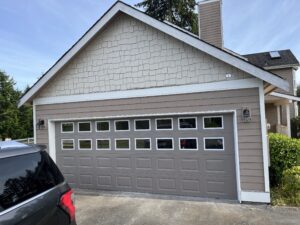 Remodeled garage with a wide single gray door replacing two doors.