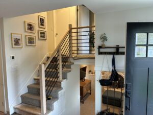 Foyer view of custom wooden stair railing with black metal spindles.
