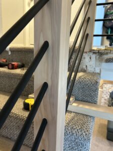 Detailed view of custom stair railing with black iron spindles.