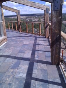 Elevated outdoor deck with tiled floor, wooden posts, and valley view.